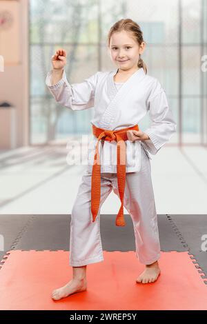 Selbstbewusstes Mädchen in Karate-Uniform posiert auf der Matte Stockfoto