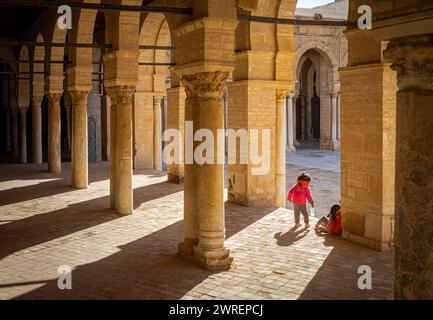 Zwei kleine Kinder im Innenhof der Großen Moschee von Kairouan oder Moschee von Uqba in Kairouan, Tunesien. Stockfoto