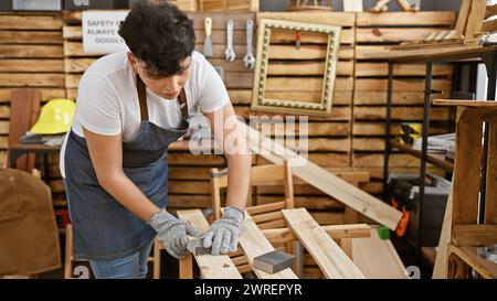 Ein junger erwachsener Mann schleift Holz in einer gut organisierten Tischlerei und zeigt handwerkliches Können und Handarbeit. Stockfoto