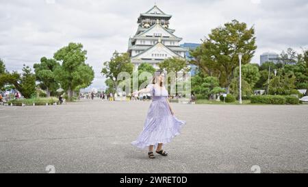 Wunderschöne hispanische Frau, die sich in einem atemberaubenden Kleid um das alte Schloss osaka dreht - ein heiteres Urlaubs-Highlight inmitten japanischer Tradition Stockfoto