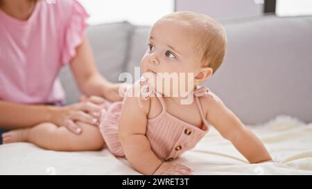 Schöne Mutter massiert die Beine der Baby-Tochter zu Hause, ein schöner Ausdruck der Liebe, des Familienlebens und der Hautgesundheit Stockfoto