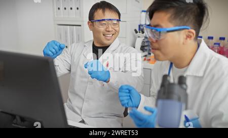 Zwei Männer arbeiten zusammen in einem Wissenschaftslabor und analysieren die Ergebnisse auf einem Computer. Stockfoto