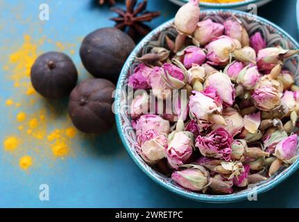 Getrocknete Rosenknospen aus nächster Nähe. Rosenblüten in einer blauen Keramikschale. Kräutertee-Zutat. Blauer Hintergrund mit Kopierraum. Stockfoto