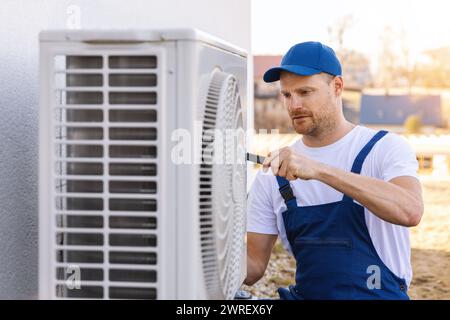 Techniker, der an der Klimaanlage oder an der Außeneinheit mit Wärmepumpe arbeitet. Wartung, Wartung und Reparatur der Klimaanlage Stockfoto
