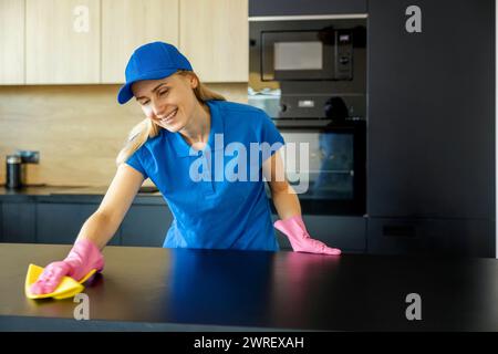 Ein lächelnder Putzservice-Mitarbeiter arbeitet in der Küche zu Hause Stockfoto