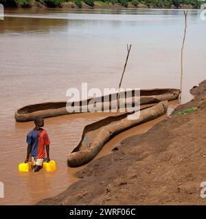 OMO VALLEY, ÄTHIOPIEN - 23. NOVEMBER 2011: Der Mann sammelt Wasser in Kanistern aus dem Omo River bei Turmi am 23. November 2011 im Omo Valley, Äthiopi Stockfoto