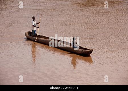 OMO VALLEY, ÄTHIOPIEN - 23. NOVEMBER 2011: Äthiopische Männer überqueren am 23. November 2011 in Omo Valley in Äthiopien den Omo River bei Turmi mit einem Holzboot Stockfoto