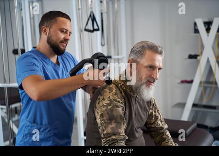 Physiotherapeut führt eine Hardware-Massage auf dem Rücken eines Militärs durch Stockfoto