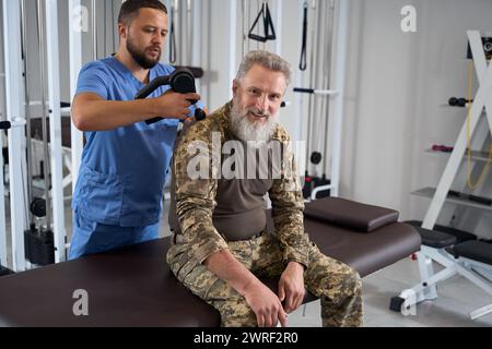 Der Arzt führt Hardware-Rückenmassage für Soldaten in der Rehabilitation durch Stockfoto