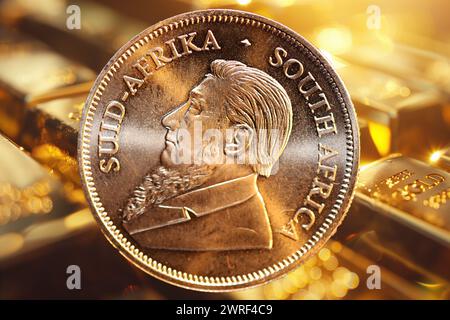 Nahaufnahme einer Krugerrand-Goldmünze, im Hintergrund verschwommene Goldbarren (Komposition) Stockfoto