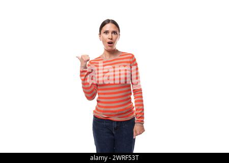 Junge europäerin mit schwarzem Haar, die überrascht auf den Zeigefinger zeigt Stockfoto