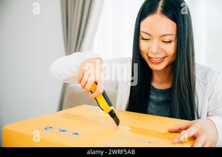 Eine Frau hält einen Universalschneider für präzises Auspacken und enthüllt Online-Shopping-Inhalte Stockfoto