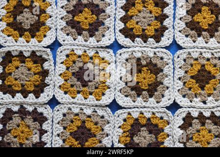 Häkeln Sie Ornament aus nächster Nähe. Granny Quadrate aus natürlichem Bio-Wollgarn. Gemütlicher Herbstabend. Hobby- und Freizeitkonzept. Weiche Garnstruktur Stockfoto