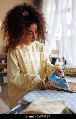 Vertikales Porträt einer jungen Frau mit flippiger Lockenhaarbügelkleidung zu Hause und bei der Arbeit im Kopierraum Stockfoto