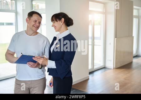 Zufriedener Käufer unterzeichnet Dokumente für den Kauf eines Hauses Stockfoto