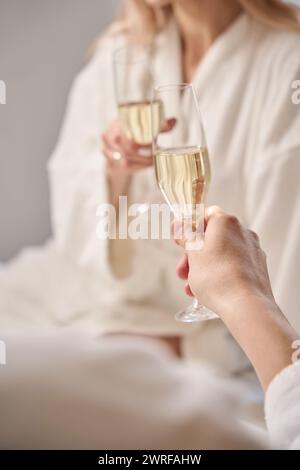 Ein romantisches Paar mit einem Glas Champagner saß auf einem großen Bett Stockfoto