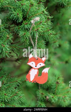 Hölzerne Weihnachtsdekoration auf einer grünen Tanne. Nahaufnahme eines umweltfreundlichen, handgefertigten Weihnachtsschmucks. Stockfoto
