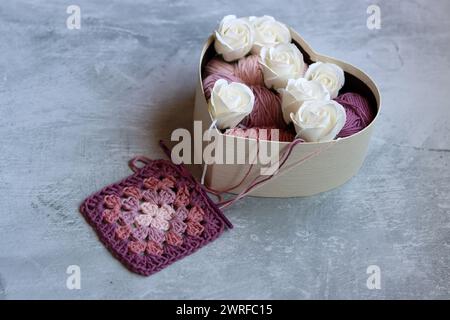 Blumenstrauß aus Baumwollgarnkugeln in einer Holzkiste. Farbenfrohes Foto von weichem rosa Bio-Garn. Hobbys und Freizeitkonzept. Stockfoto