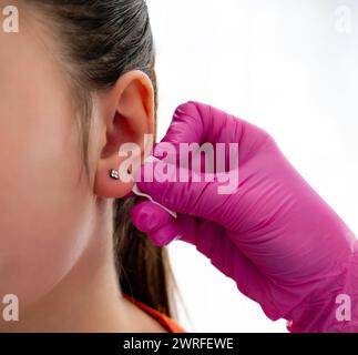 Das Ohr des Kunden wurde vom professionellen Arzt durch einen Punkt mit Hilfe des speziellen Stiftes für das Piercing in einem Schönheitssalon markiert. Hochwertige Fotos Stockfoto