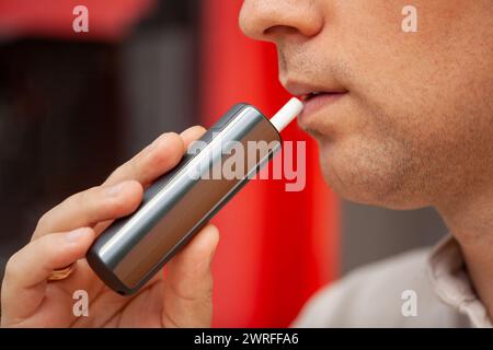 Ein Mann hält eine elektronische Zigarette in der Hand, die er in seiner Freizeit rauchen will. Stockfoto