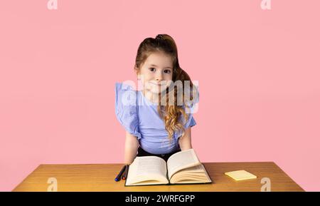 Ein kleines Mädchen, das beim Lesen von Büchern erwischt wurde und sehr überrascht war, was sie in dem Buch schrieb. Das kleine Mädchen mag die Schule sehr und sie mag den SC Stockfoto