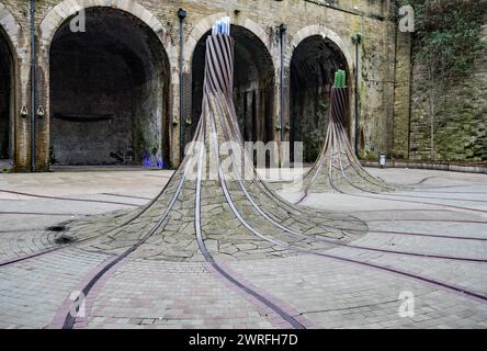 „Fibres“, eine standortspezifische Skulptur am St. Blaise Square, in der Nähe des Bahnhofs Forster Square, alte Eisenbahnlinien, kurvenförmige Säulen und Optik. Stockfoto