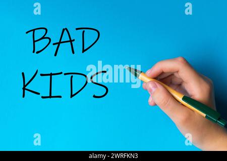 Kinder Hand mit Stift schreiben auf blauweißem Hintergrund. Schreibhand. "Schlechte Kinder" Stockfoto