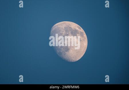 Klare Sicht auf die Mondoberfläche während der wachsenden Gibbous-Phase vor einem Dämmerungshimmel Stockfoto