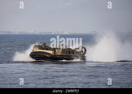 Luftpolsterpiloten der US Navy waten während eines LCAC-Tauschs mit der japanischen Seefahrtruppe über das Meer Stockfoto