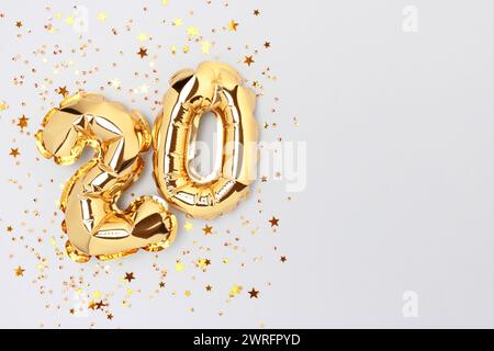 Zahl zwanzig goldene Folienballons mit Sternenkonfetti auf blauem Hintergrund. Stockfoto