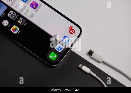 IPhone, das als Hintergrund ein Schwarzweißbild hat, das zeigt, dass auf der schwarzen Farbe das alte Ladegerät und auf dem weißen das neue Typ c ist Stockfoto