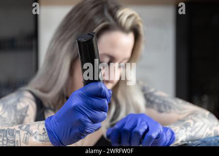 Horizontales Foto der fokussierte Blick einer Tätowiererin richtet sich auf ihr Handwerk, während sie die Tätowiermaschine mit einer Mischung aus Finesse und Selbstvertrauen handhabt. Konzeptbus Stockfoto