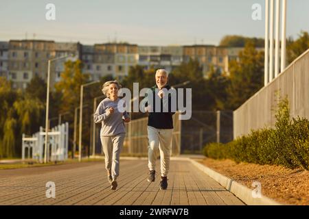 Aktive Seniorenpaare genießen Laufen, sportliche, körperlich aktive, ältere Männer und Frauen beim Outdoor-Joggen Stockfoto