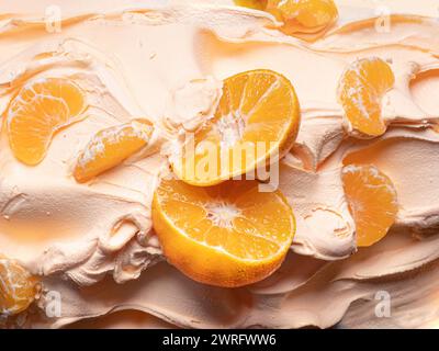 Frozen Tangerine Flavour Gelato - Vollformat Detail. Nahaufnahme einer orangefarbenen Oberflächenstruktur von Eiscreme, die mit Stücken von Mandarinenfrüchten bedeckt ist. Stockfoto