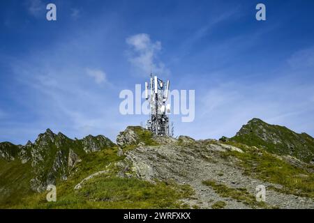 Metallturm mit verschiedenen Telekommunikationsantennen auf einem Berg, vor blauem Himmel, im Frühjahr. Sicherstellung des Betriebs von Stockfoto