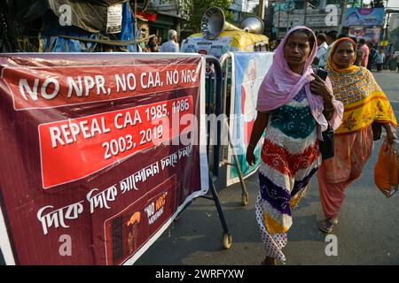 Kalkutta, Indien. März 2024. Zwei Frauen gehen während einer Demonstration an einem Banner vorbei, nachdem die Zentralregierung die Umsetzung des Bürgerschaftsgesetzes (Amendment) von 2019 in Kalkutta mitgeteilt hatte. (Foto: Dipayan Bose/SOPA Images/SIPA USA) Credit: SIPA USA/Alamy Live News Stockfoto