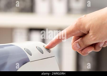 Zugeschnittene Aufnahme eines nicht erkennbaren Mannes, der die Taste auf dem Bedienfeld des Druckers drückt. Druckerscanner Laserdrucker Bürokopierer Zubehör Start Konzept Stockfoto