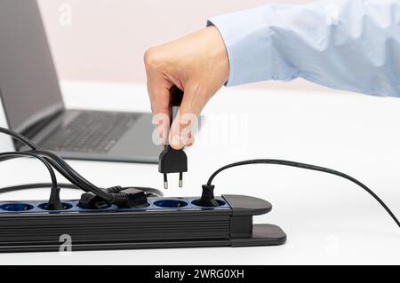 Nahaufnahme einer Frau die Hand stecken einen Stecker in eine Steckdose auf einem Tisch zu Hause Stockfoto