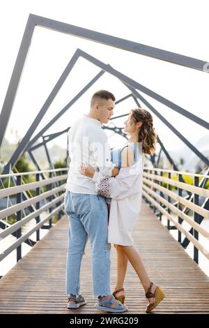 Ein Mann und eine Frau stehen auf einer Brücke, mit Blick auf das Wasser darunter. Sie scheinen an Gesprächen beteiligt zu sein oder die Aussicht zu genießen. Stockfoto