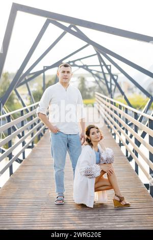 Ein Mann und eine Frau stehen auf einer Brücke und blicken über das Wasser. Sie haben beide ihre Hände in der Tasche und scheinen tief im Schuss zu sein Stockfoto