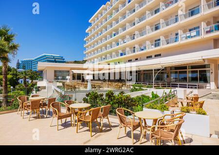 Malerische Außenfassade des Hotels mit Sitzbereich im Freien, Tischen und Stühlen für Gäste vor dem Hintergrund eines hellen, sonnigen Tages. Rhodos. Stockfoto