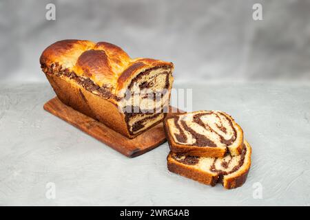 Cozonac, rumänisches traditionelles süßes Brot mit Walnussfüllung, geschnitten, Seitenansicht isoliert auf grauem Hintergrund Stockfoto