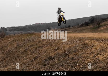 Eine Person mit Helm schwebt auf einem Motocross-Bike durch den Himmel, die Räder drehen sich und die Sportausrüstung zeigt die Stockfoto