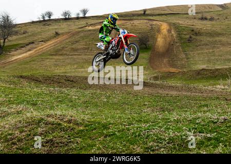 Ein Motorradrennfahrer auf einem Dirt Bike schwebt durch die Luft und trägt einen Helm zum Schutz. Die Räder und Reifen des Fahrzeugs drehen sich dabei Stockfoto