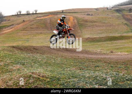 Ein Motorradrennfahrer fährt mit einem Dirt Bike auf einer Feldpiste und trägt einen Helm zum Schutz. Die Reifen und Räder des Fahrzeugs sind wichtige Sportgeräte Stockfoto