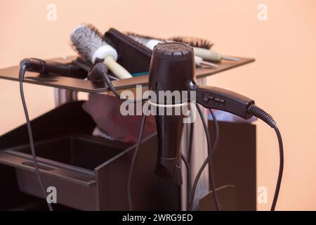 Auf dem Schreibtisch des Friseurs befinden sich Haarfön, Kämme, Lockenwickler und Glätteisen aus nächster Nähe im Schönheitssalon. Stockfoto