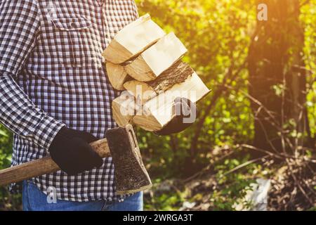 Männlicher Holzfäller im schwarz-weißen karierten Hemd mit einer Axt, die einen Baum im Wald hackt. Stockfoto