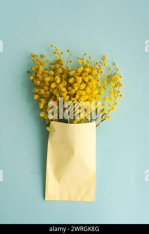 Blick von oben auf einen Haufen gelber Mimosa-Blüten in einem Umschlag auf einem Tisch Stockfoto