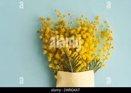 Blick von oben auf einen Haufen gelber Mimosa-Blüten in einem Umschlag auf einem Tisch Stockfoto