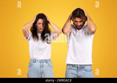 Belastete Männer und Frauen mit Händen auf dem Kopf, die einen Ausdruck von intensivem Stress oder Kopfschmerzen zeigen Stockfoto